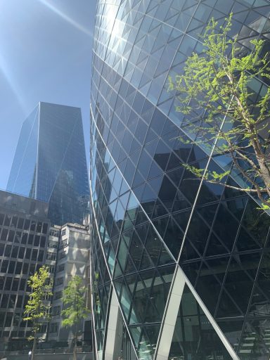 Modern skyscrapers with reflective glass façades and greenery in urban setting.